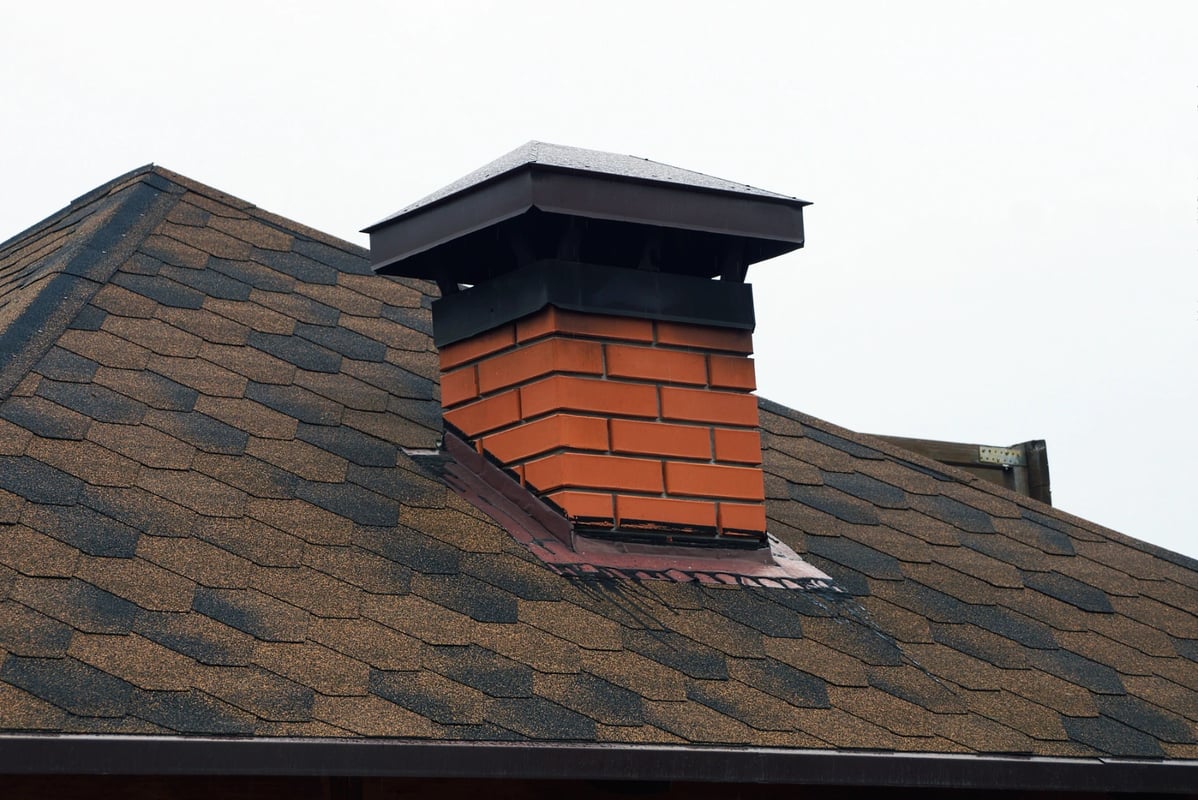 A brick chimney with a black chimney cap