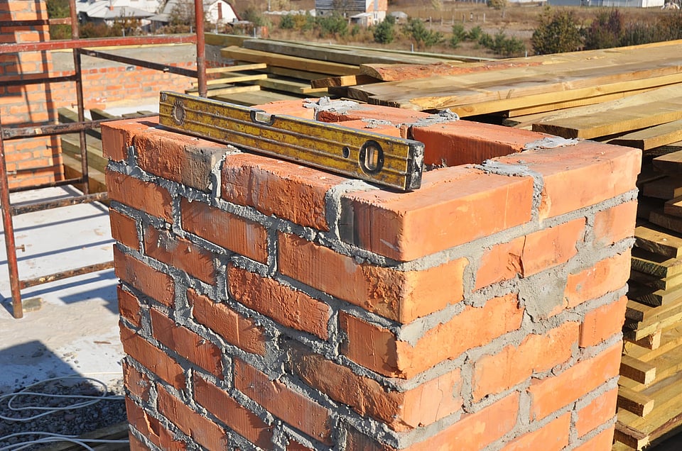 Adobe Stock image of a chimney that has a level on top of it and needs repairs.