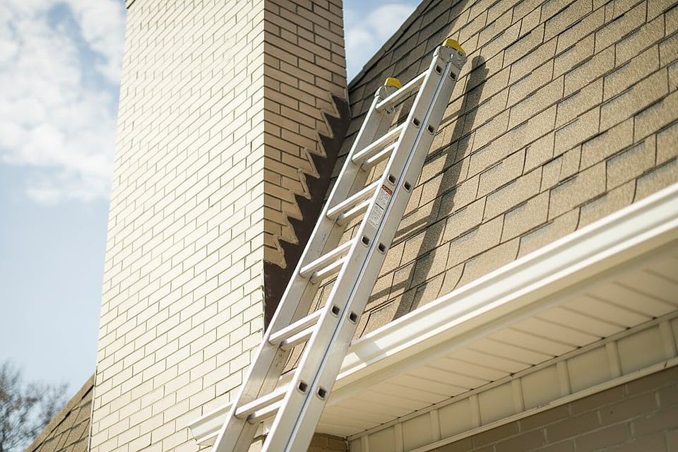 A ladder propped up on a roof near a chimney — Suffolk County NY chimney sweep and fireplace inspection by Alpine Chimney Sweeps