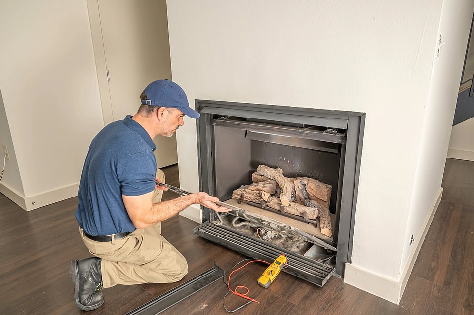 Adobe Stock image of a maintenance worker completing a gas fireplace repair.