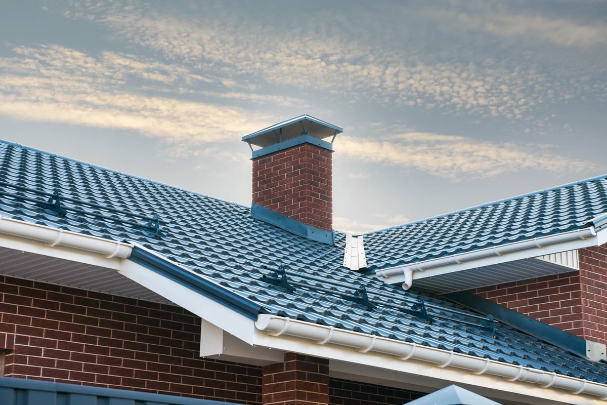 Masonry chimney with a chimney cap and clouds in the background - Alpine Chimney Sweeps