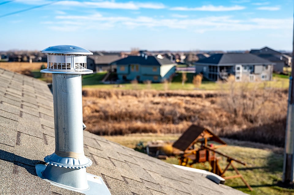 Adobe Stock image of a metal flue pipe coming out of a roof.