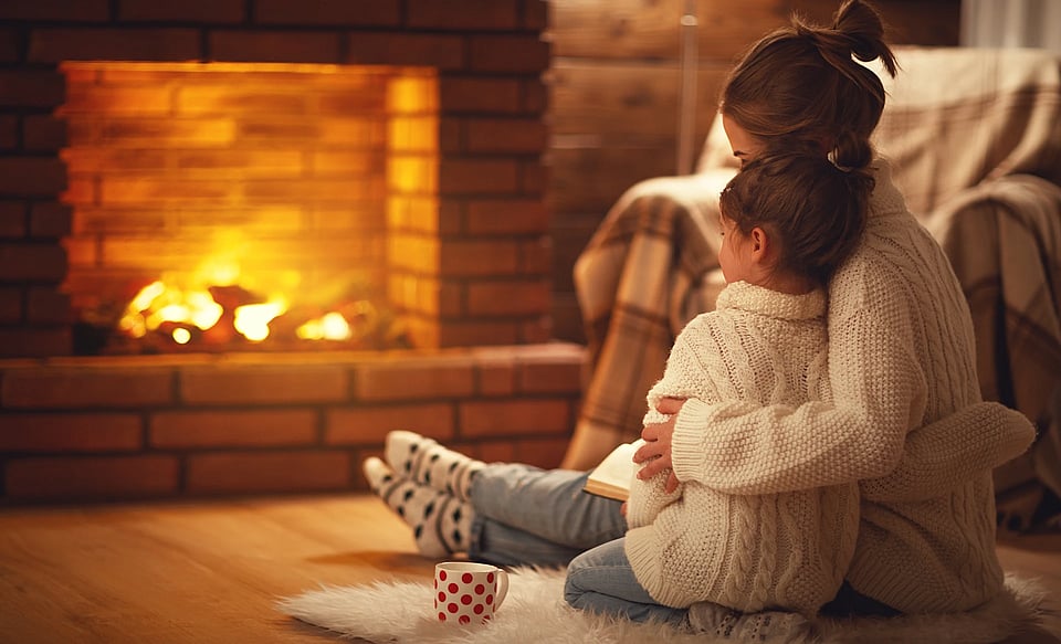 Adobe Stock image of a mother and daughter sitting by a fireplace.