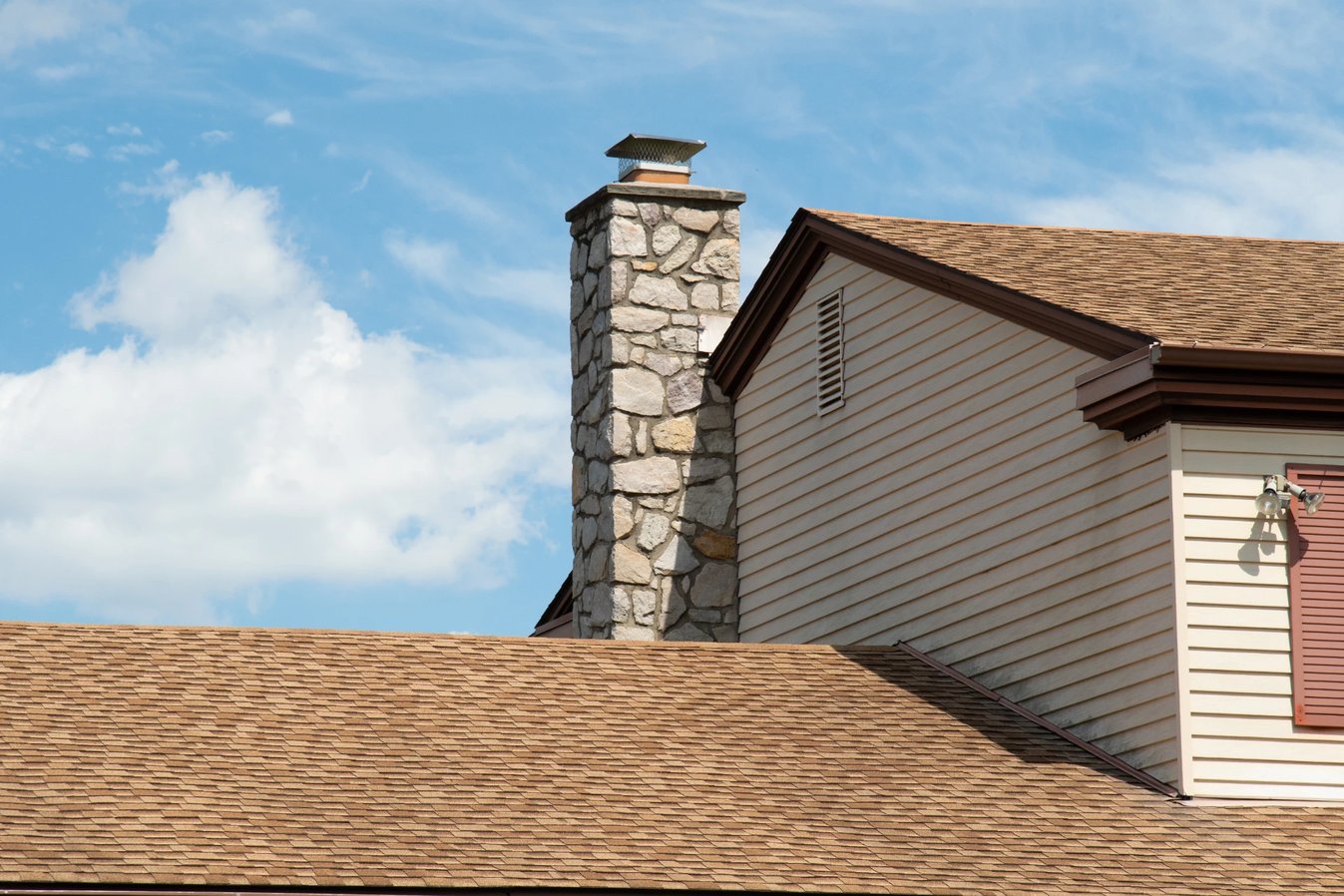 Adobe Stock image of a stone chimney with a metal chimney cap.