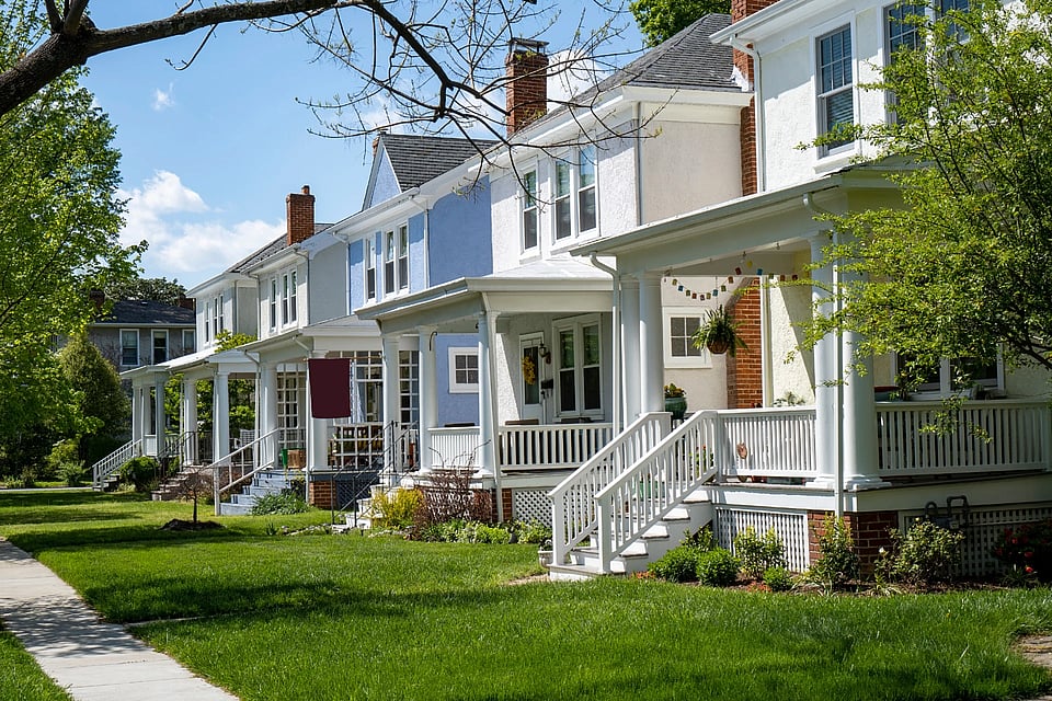 Adobe stock image of homes with chimneys and porches on a street.