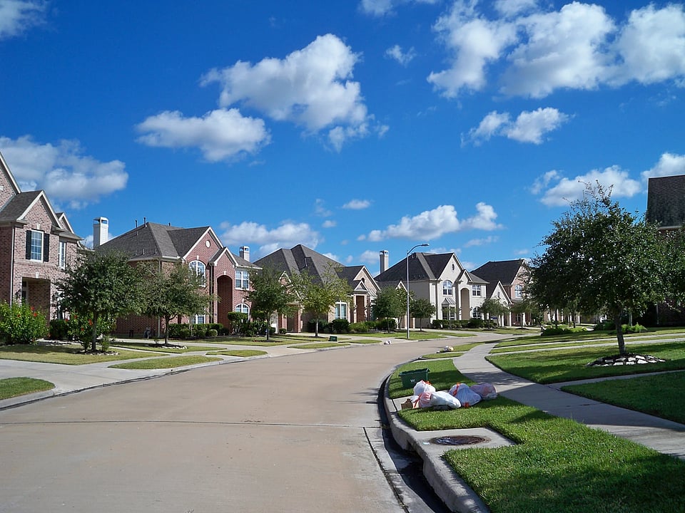 Adobe Stock image of houses on a street with trees in front.
