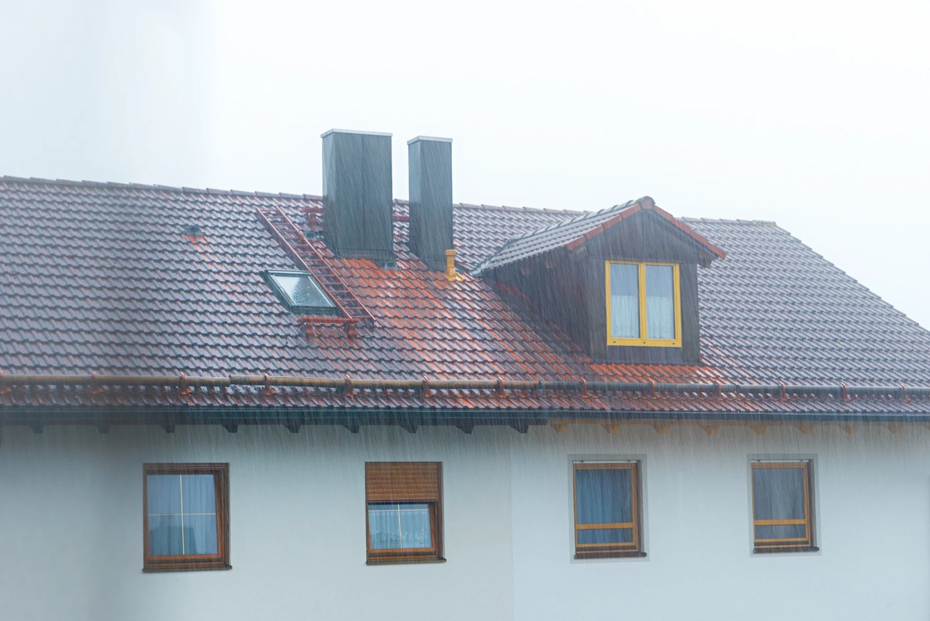 Adobe Stock image of rain coming down on a house with two chimneys.