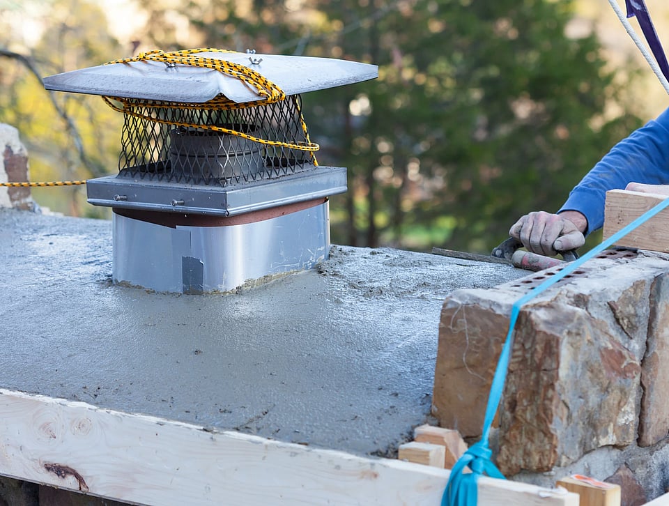 Adobe Stock image of someone repair a chimney crown.