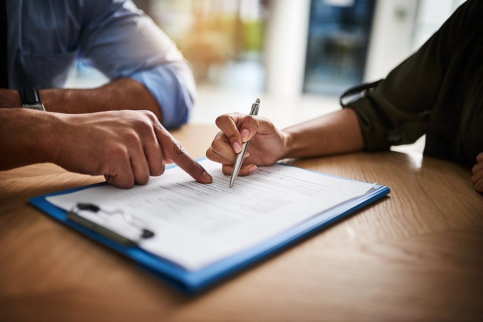 Adobe Stock image of two people looking at paperwork on a clipboard.
