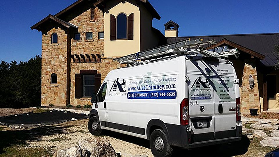 Atlas Chimney professional van parked in front of a stone house