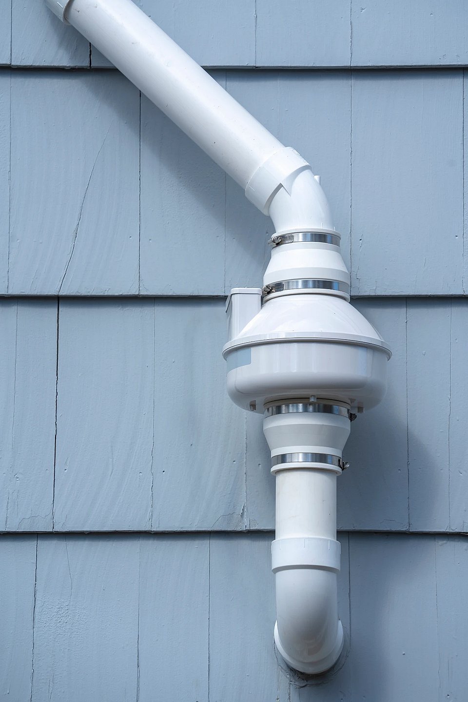 Adobe Stock image of a radon mitigation system on a blue house.