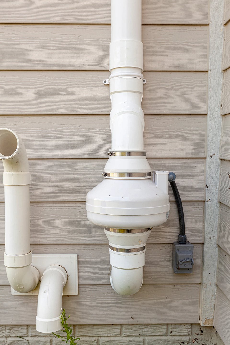 Technician installing radon mitigation fan on exterior wall
