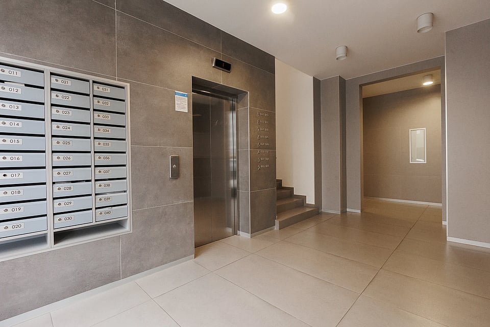 Adobt Stock image of the front lobby of an apartment complex featuring stairs and an elevator.