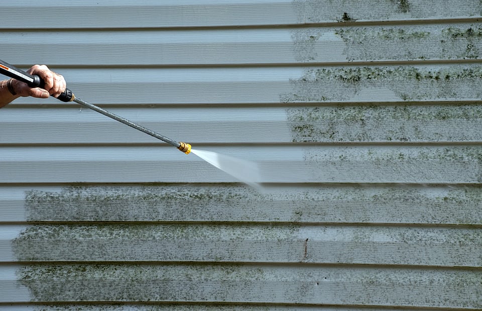 Adobe Stock image of someone soft washing a home.