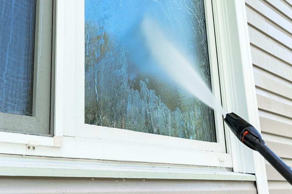 Technician installing radon vent pipe against brick exterior