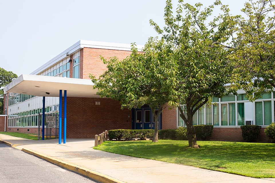 Adobe Stock image of the front entrance of a brick school building.