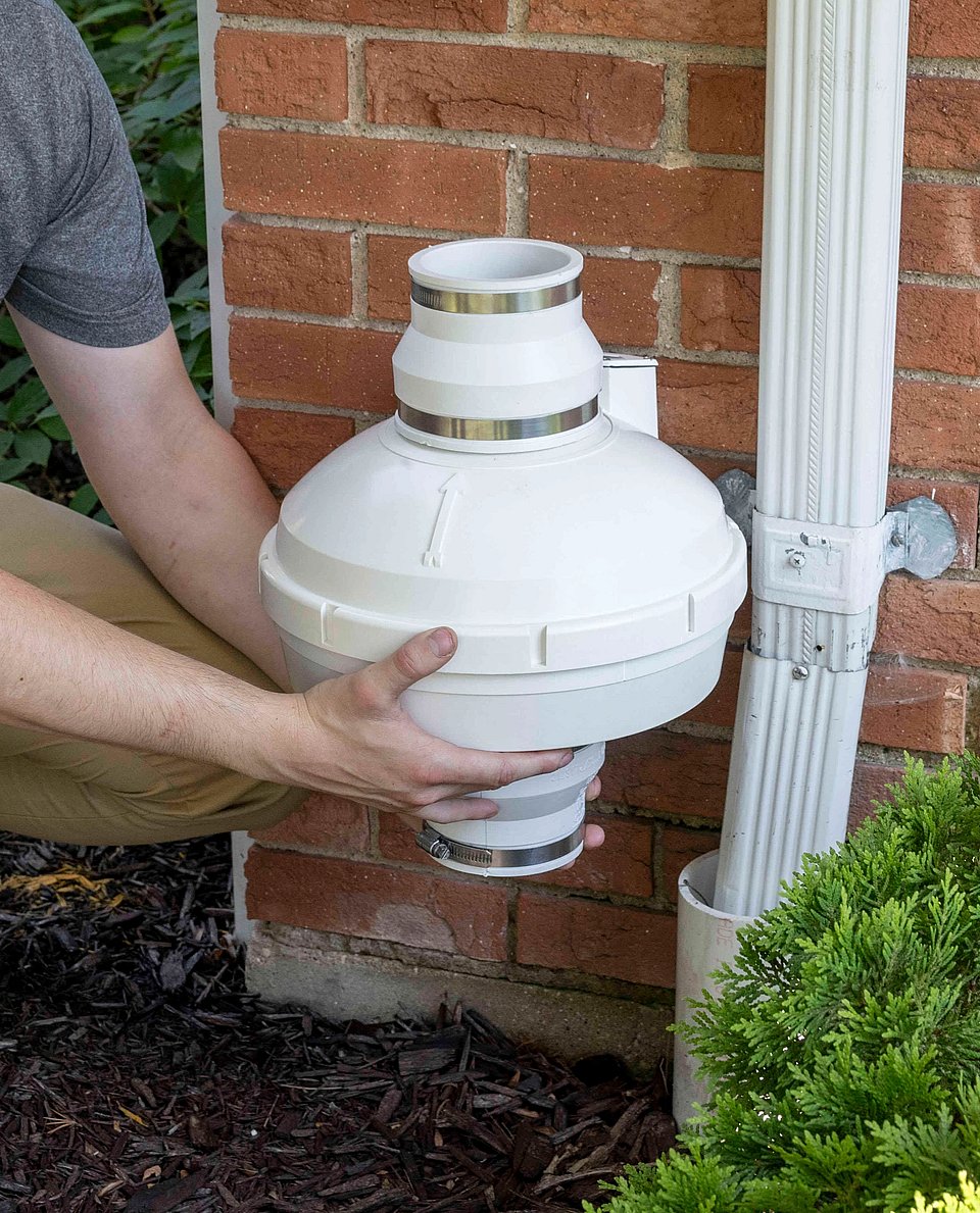 An image of a white radon fan against a brick house.