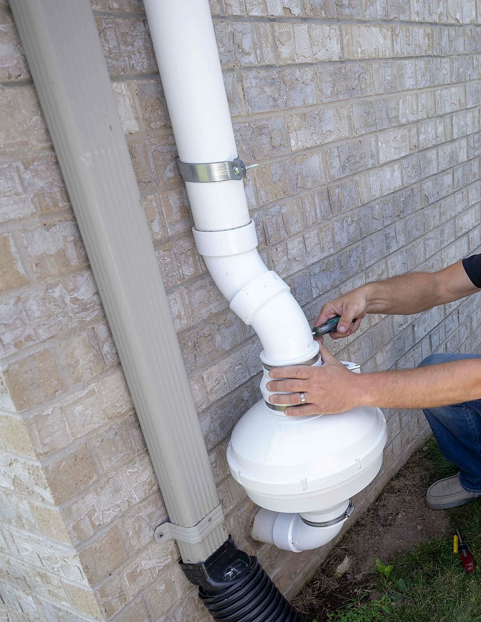 Image of a tech installing a radon mitigation system on a brick home.