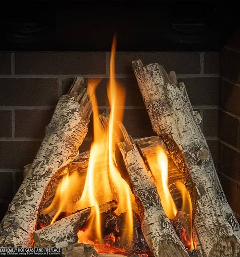 Valor gas logs in birch style with a brick background.