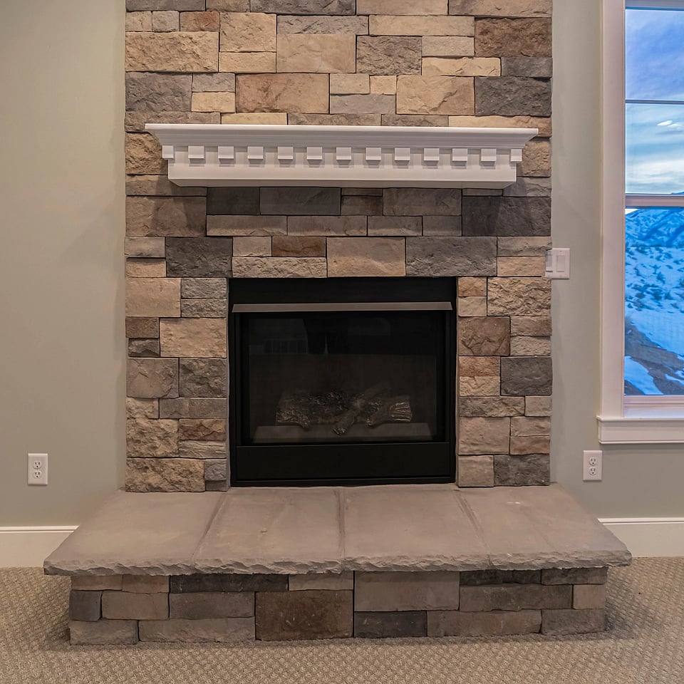 Adobe Stock image of a gas fireplace insert in a stone fireplace.
