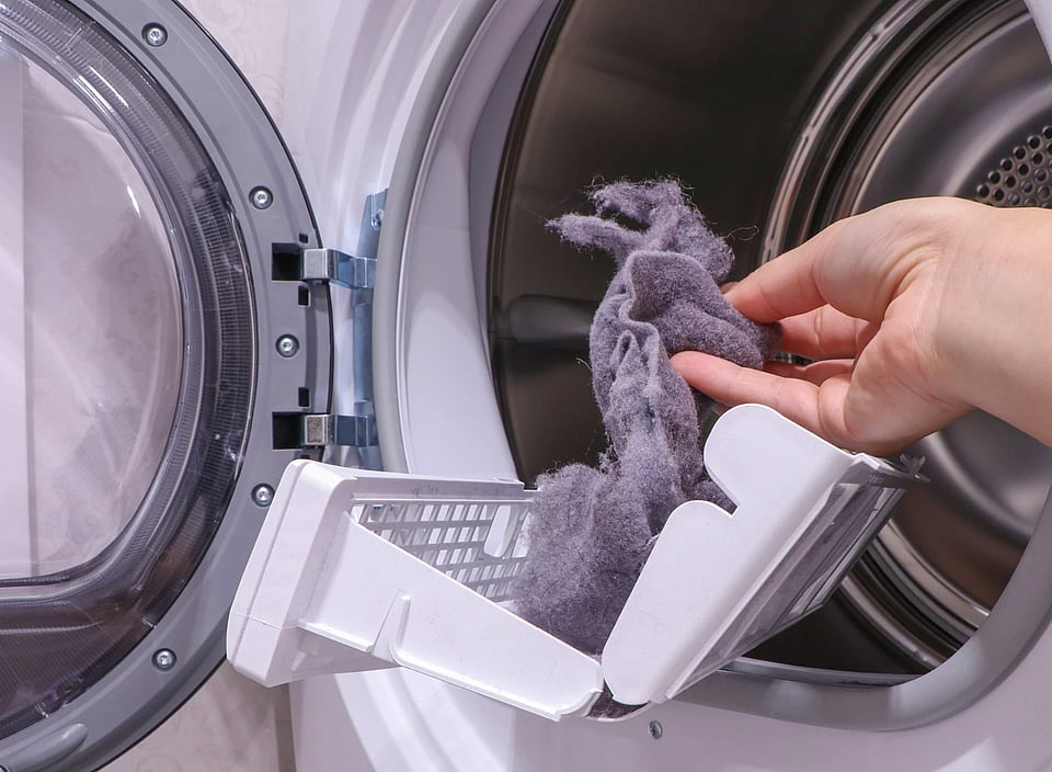 Adobe Stock image of someone removing dryer lint from a lint trap.