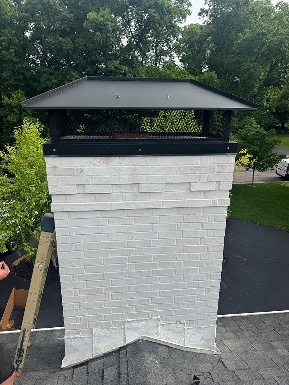 Black chimney cap installed on a white brick chimney by Blackburns Chimney.