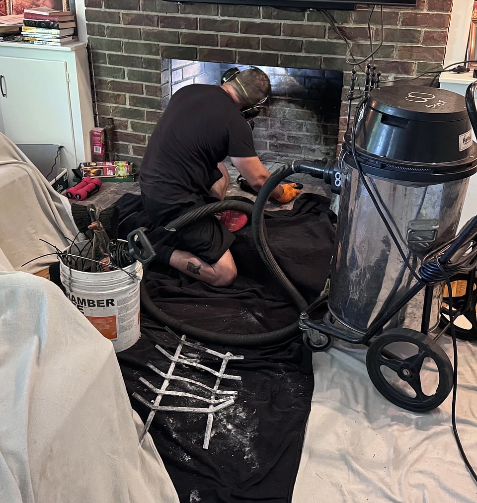 Blackburns Chimney employee sweeping a fireplace.