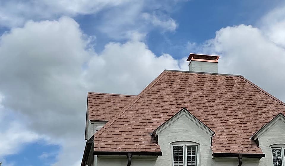 A copper chimney cap on a white masonry chimney, installed by Blackburns Chimney.