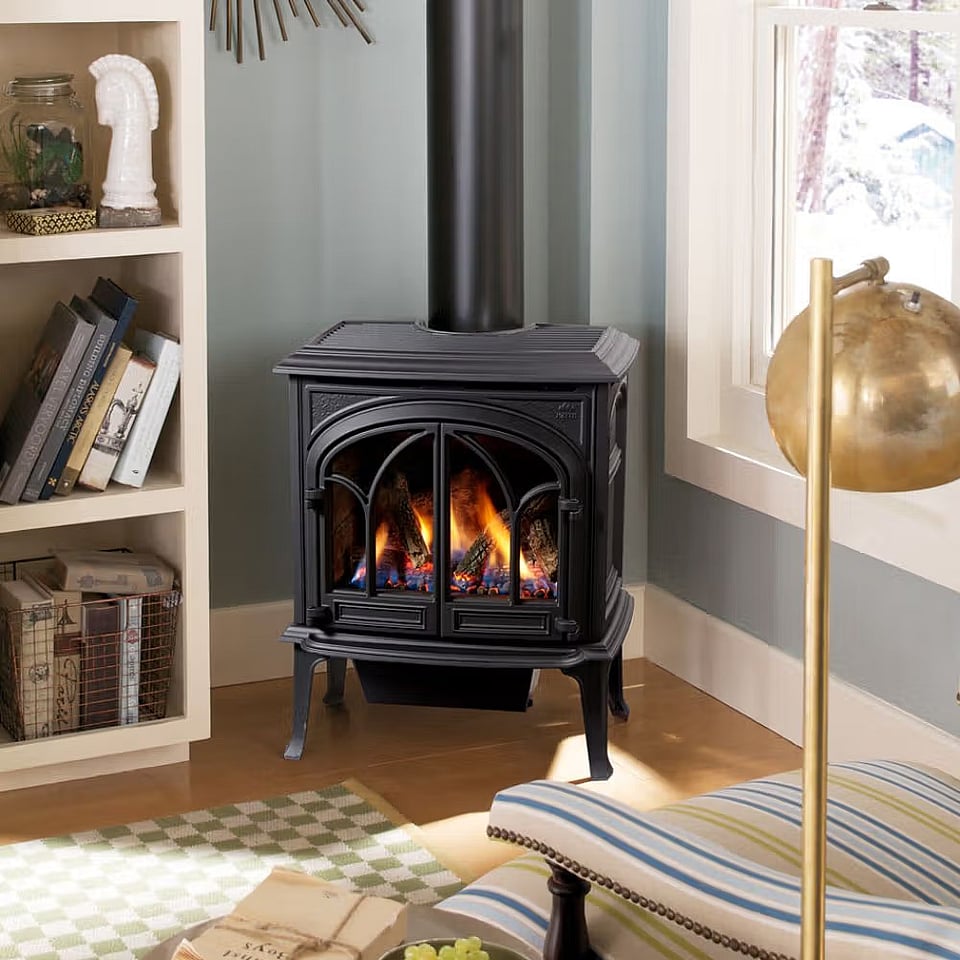 A Jotul gas stove by a bookshelf.