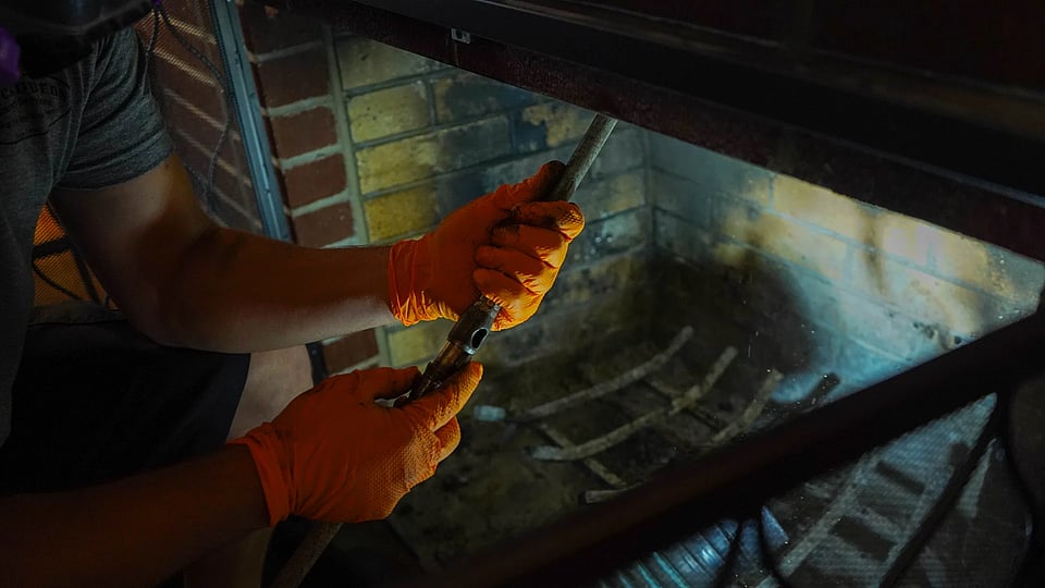 Original image from Blackburns Chimney of gloved hands cleaning a chimney flue.