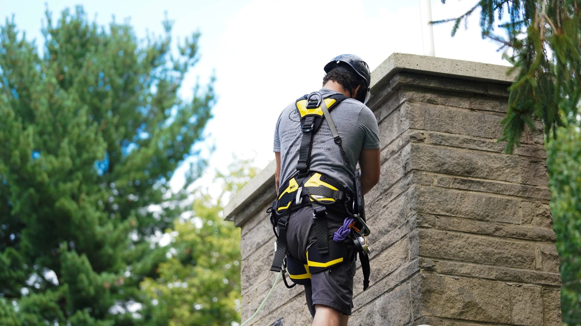 Original image of a Blackburns employee in proper harnesses inspecting the outside of a masonry chimney.