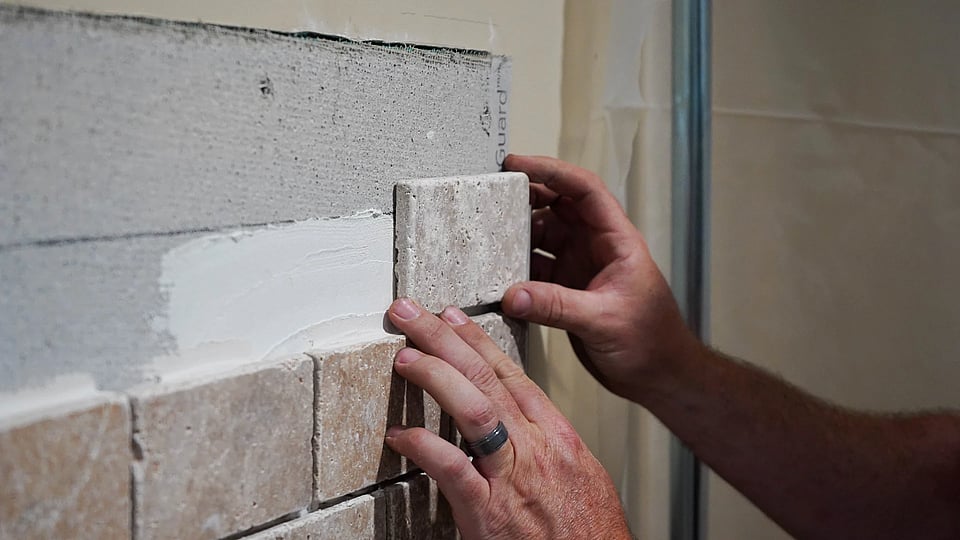 Original image of a Blackburns employee laying tile for a new fireplace