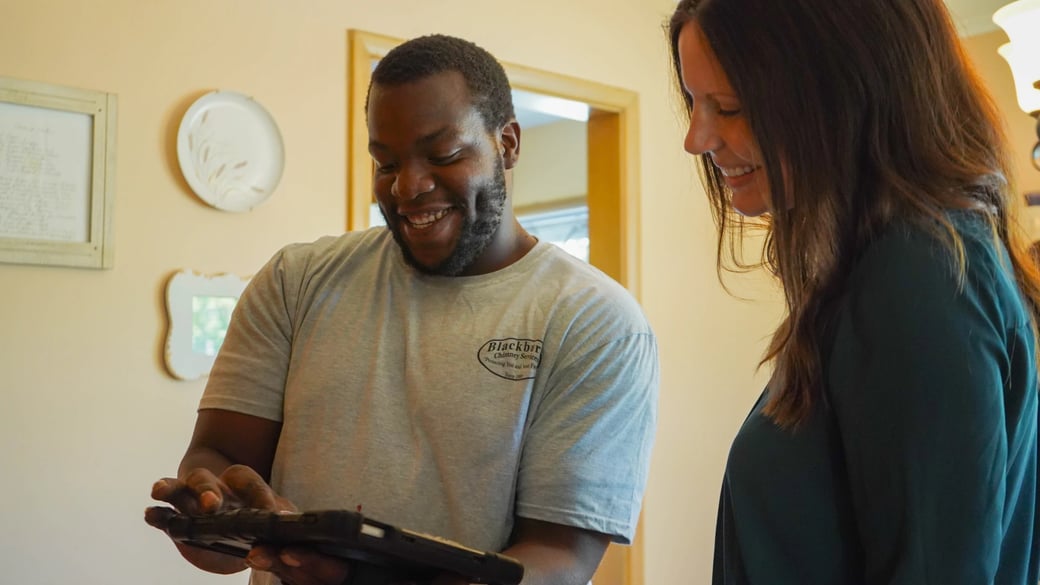 Blackburns technician showing a homeowner the results of her chimney inspection report
