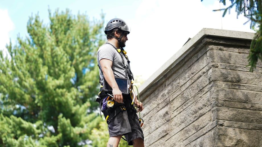 Original image of Blackburns employee examining a chimney while roped off.
