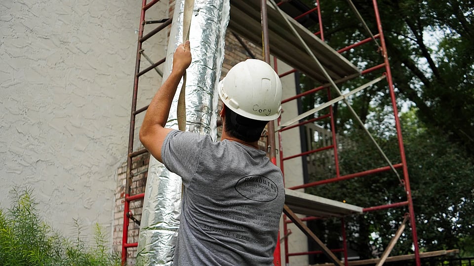 Original photo of Blackburns employee bringing a new chimney liner to a roof for installation.