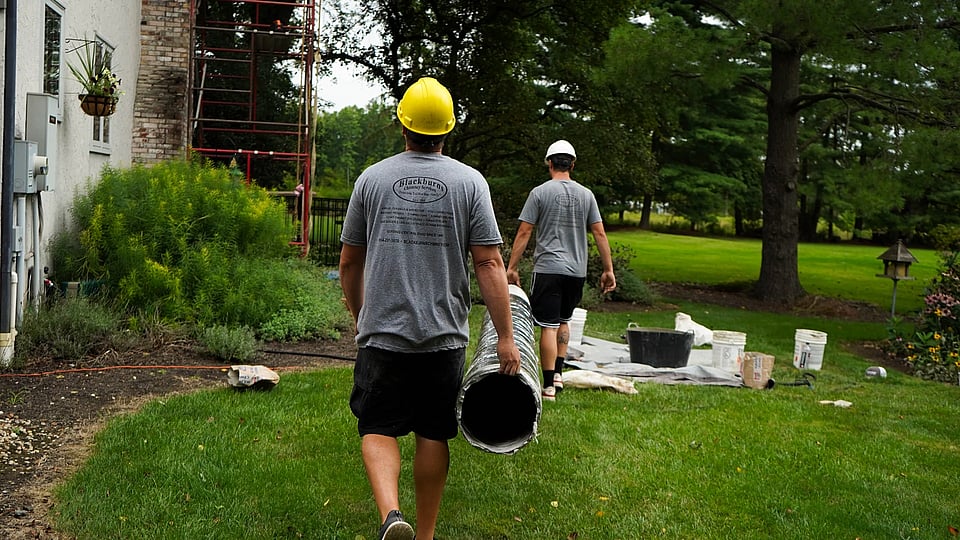 Original photo of Blackburns employees carrying a new chimney liner toward a home.