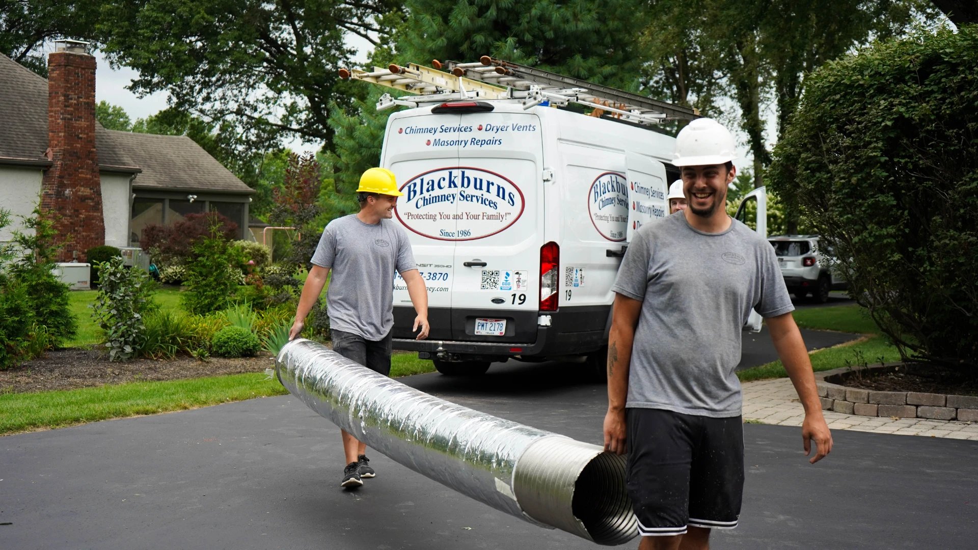 Original photo of two Blackburns employees carrying a chimney flue liner from their truck.