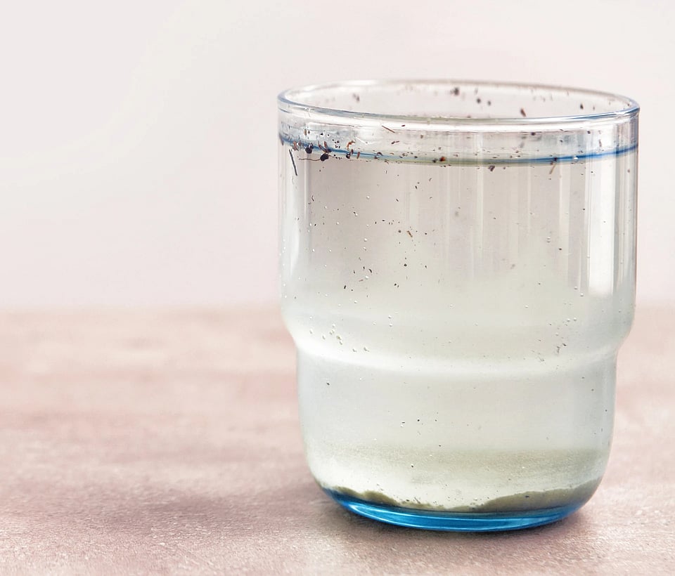 A glass of dirty, cloudy water with sediment.