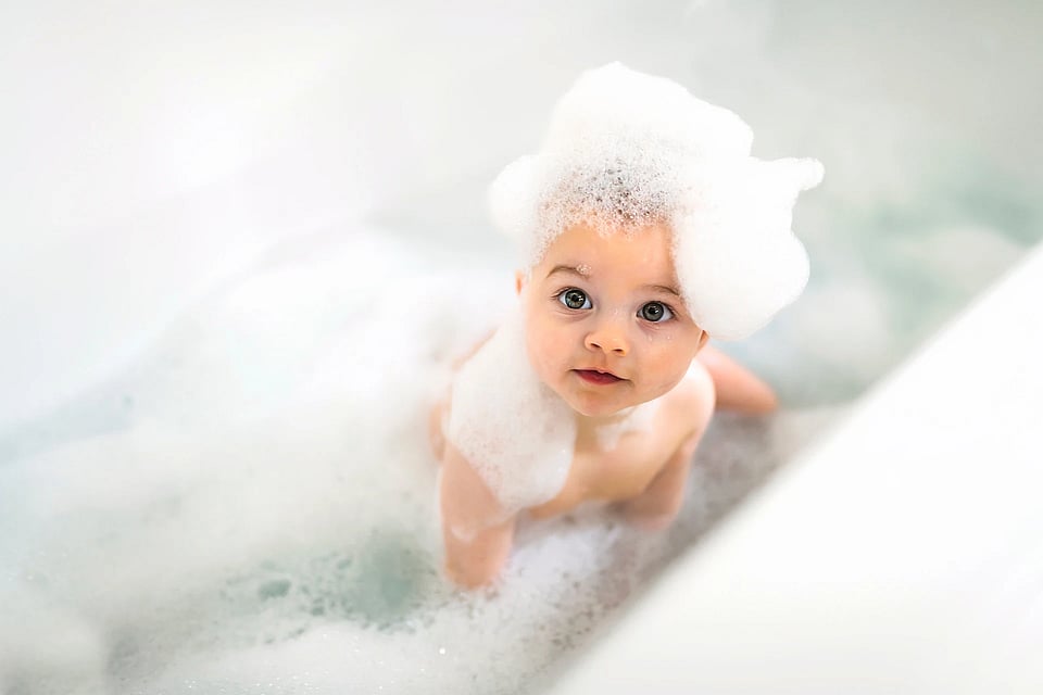 A baby in a bathtub surrounded by bubbles.
