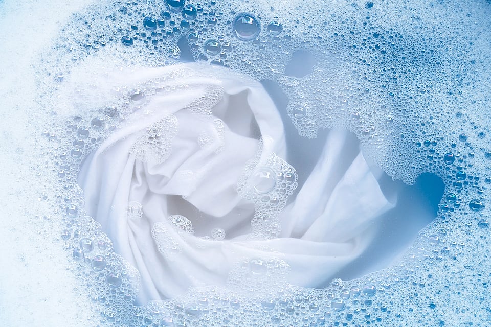 A white piece of clothing in clear water with bubbles surrounding.