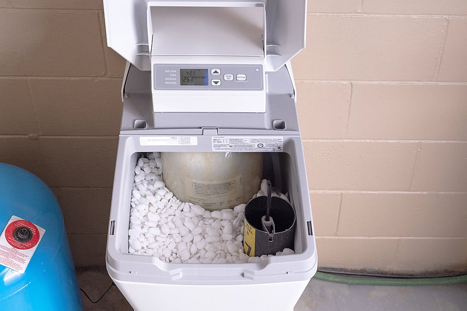 A water softener that has is open and has salt filled inside of it