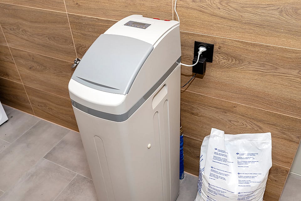 A water softener with a bag of salt sitting next to it.