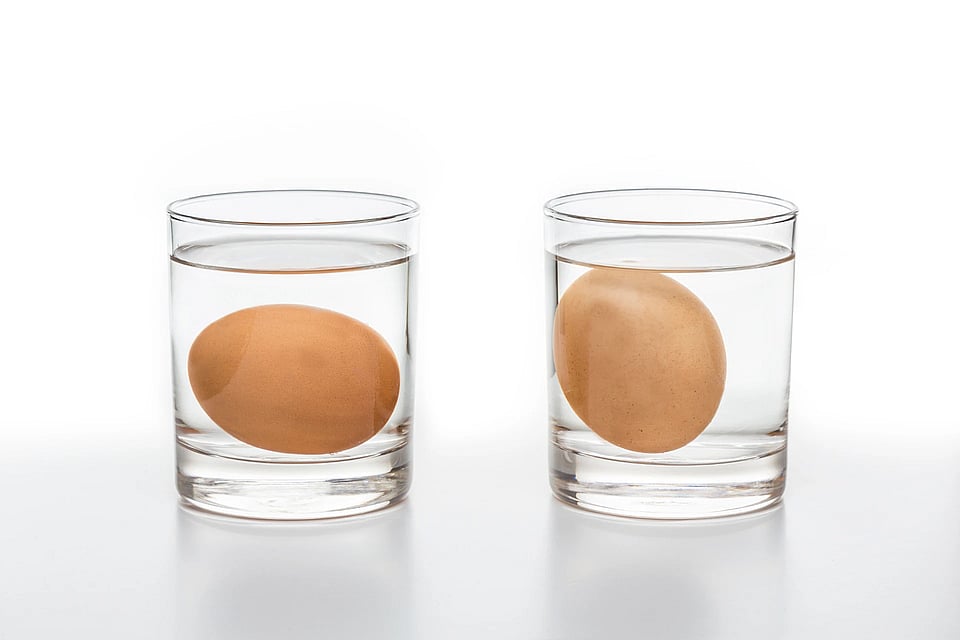 Two glasses of water, each with an egg in it, where one is floating and one is sinking.