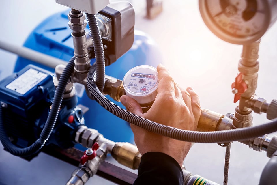 A service technician reading a pressure gauge on a water tank system.