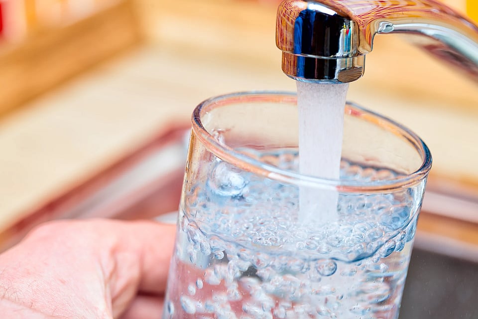Someone filling a glass of water from their sink.