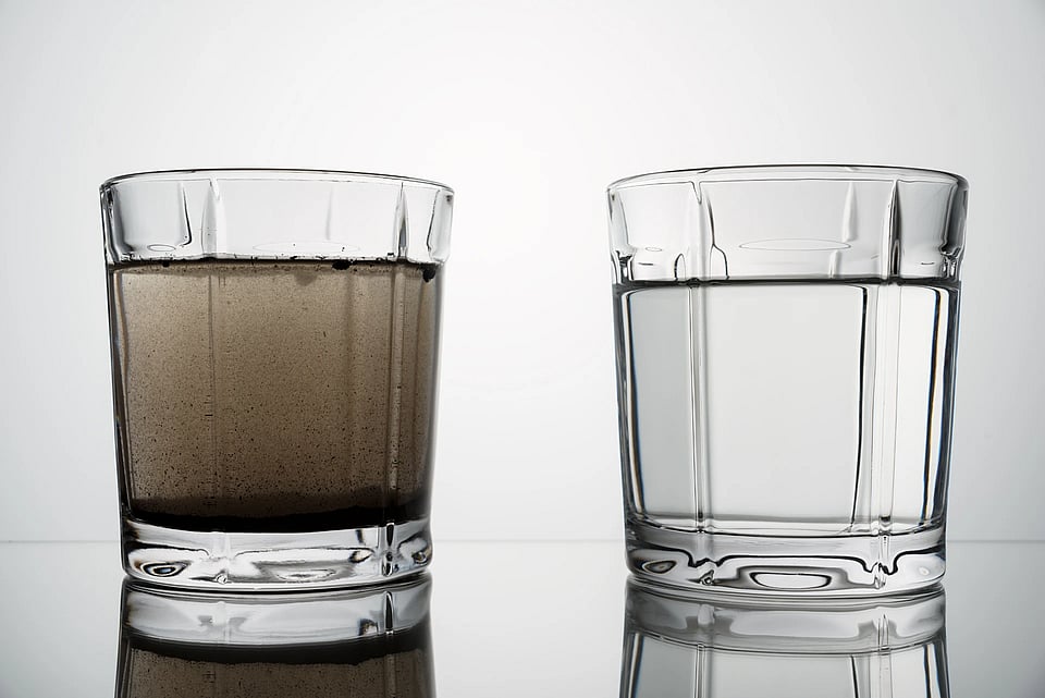 Two glasses of water - one clear and the other with dirt and sediment in it.