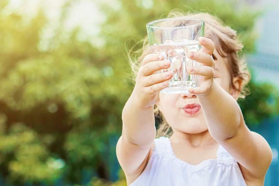 Child holding a glass of clear drinking water