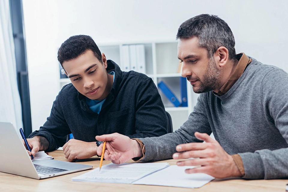 Two men working at a desk together.