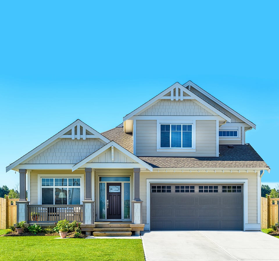 A house with a garage attached in front of a bright blue sky.