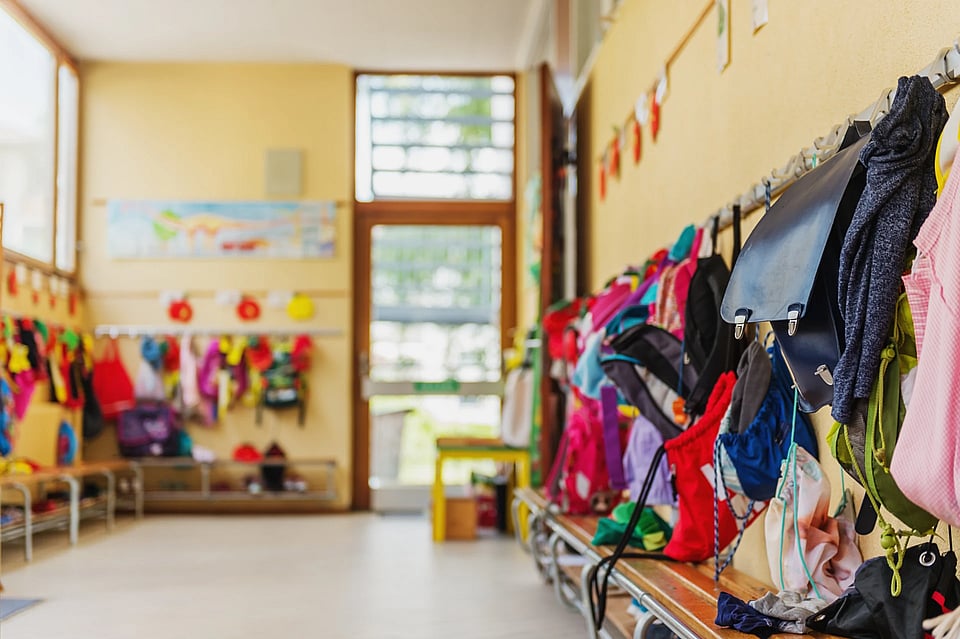 Coats and backpacks on hooks at a daycare.
